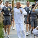 Torchbearer 131 Sir Bruce Forsyth carries the Olympic Flame on the Torch Relay leg through Kensington and Chelsea (Royal London Borough).