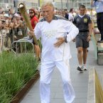 Torchbearer 131 Sir Bruce Forsyth carries the Olympic Flame on the Torch Relay leg through Kensington and Chelsea (Royal London Borough).
