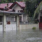A man sits on top of their roof as floods rise in suburban Quezon City, north of Manila, Philippines.
(AP Photo/Aaron Favila)