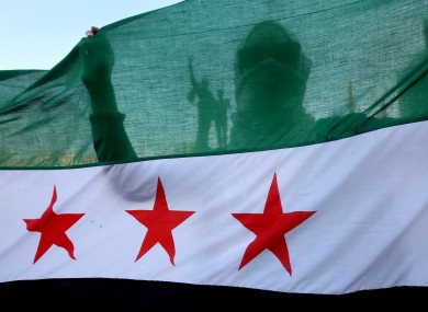A Syrian activist is silhouetted through the Syrian revolution flag.