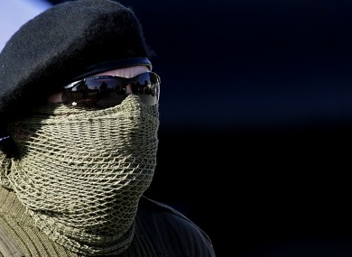 A masked dissident attends Ryan's funeral last year